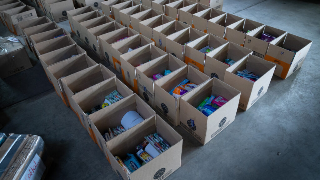 Filas de cajas con productos de aseo e higiene en la bodega de acopio