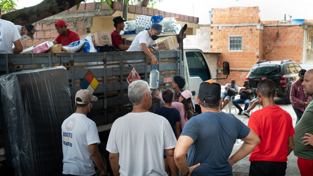Voluntarios repartiendo agua y ayuda desde un camión en una comunidad venezolana